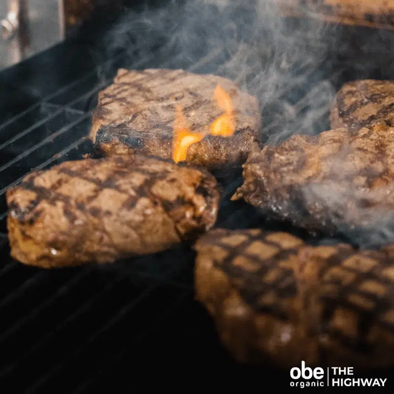 Thick organic steaks smoking on a hot barbecue grill.