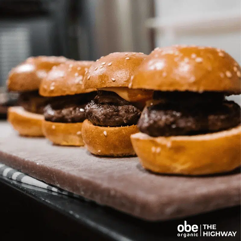 Trio of large gourmet burgers with thick patties on a tray.