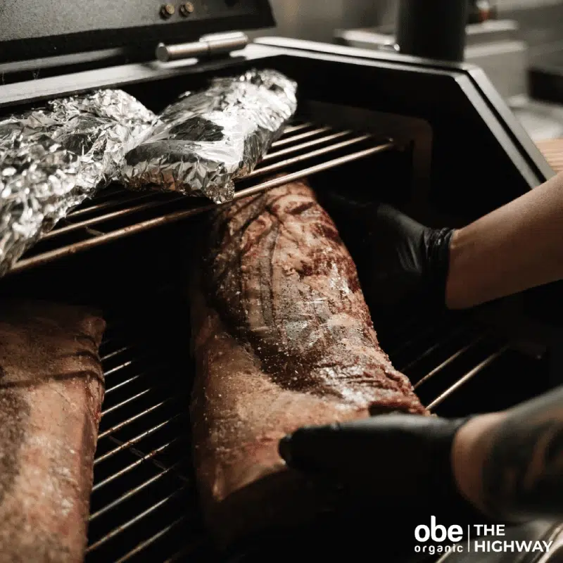 Cook slicing into grilled beef steak over a hot barbecue.