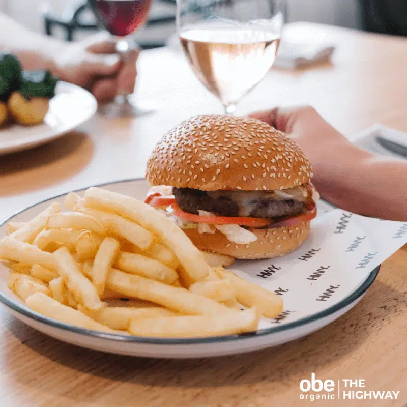 Classic cheeseburger with lettuce and fries served on a white plate.